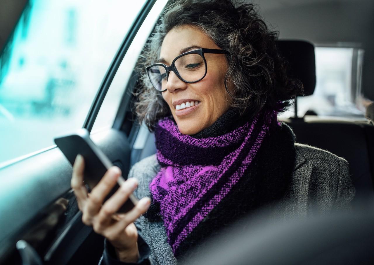 mature woman in car looking at her smartphone 